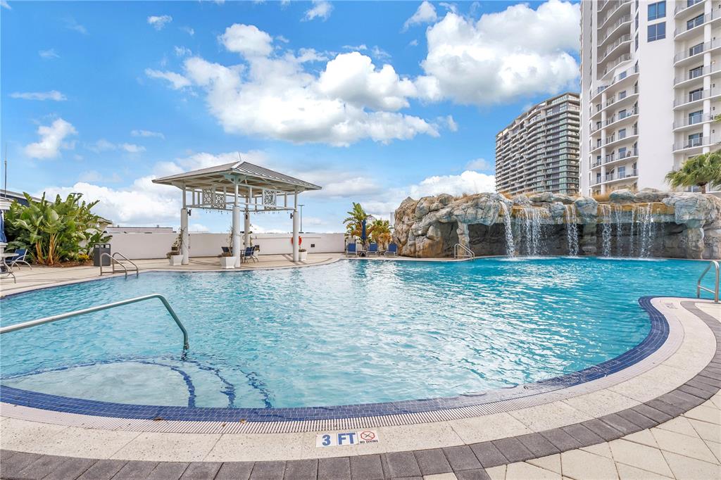 A swimming pool features a rock waterfall, a gazebo, and a tall residential building nearby — 449 S 12TH STREET UNIT 1205, TAMPA, FL