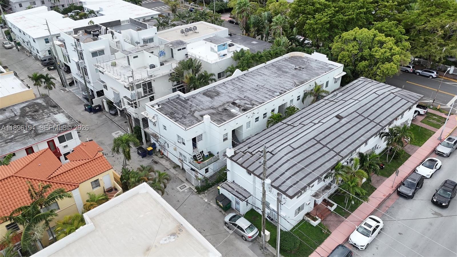 A narrow concrete walkway runs alongside a building exterior with palm trees and landscaping — 845 Michigan Ave, Miami Beach FL 33139, MIAMI BEACH, FL