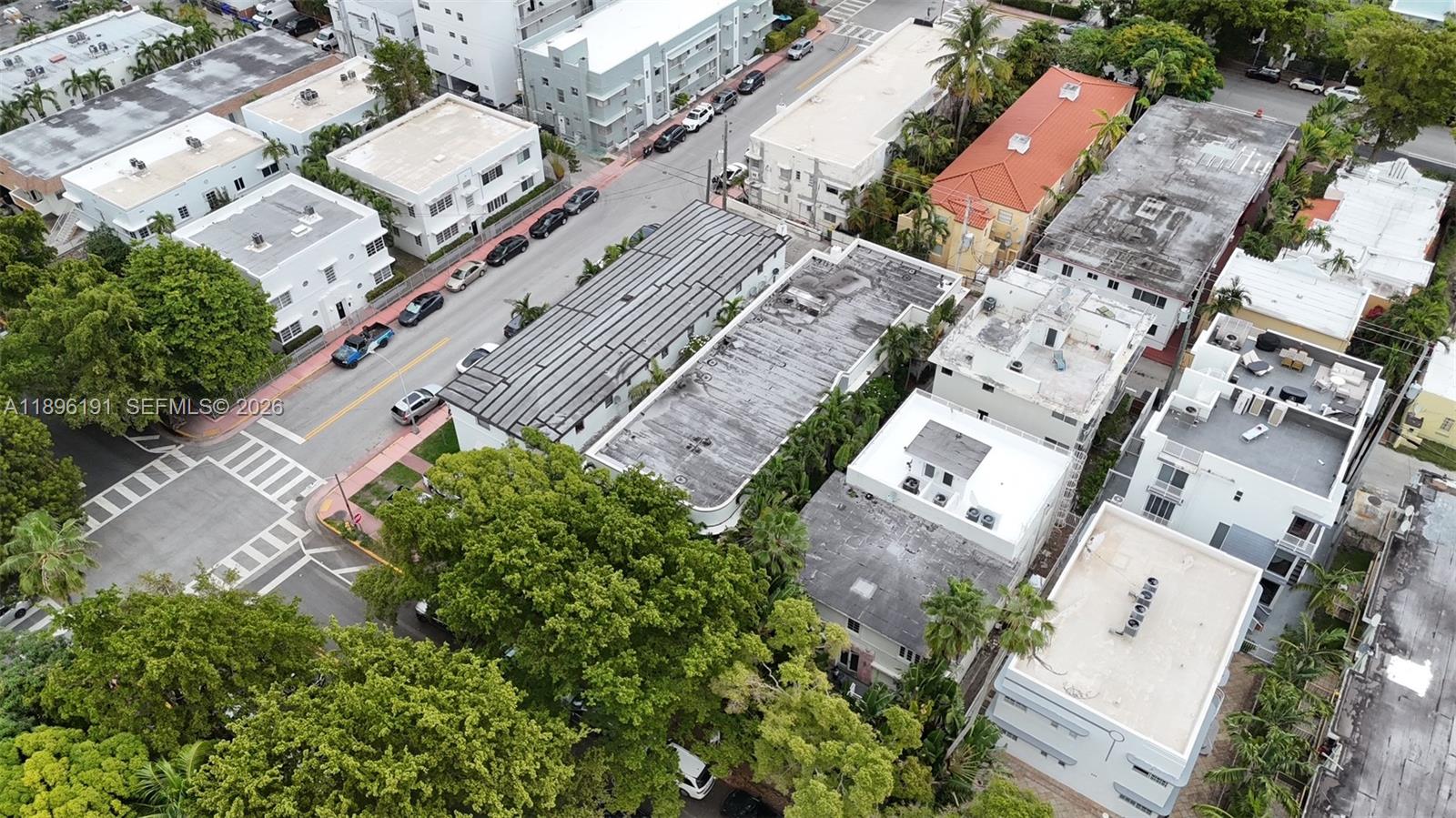 A narrow concrete walkway leads between two white buildings surrounded by lush green tropical plants — 845 Michigan Ave, Miami Beach FL 33139, MIAMI BEACH, FL