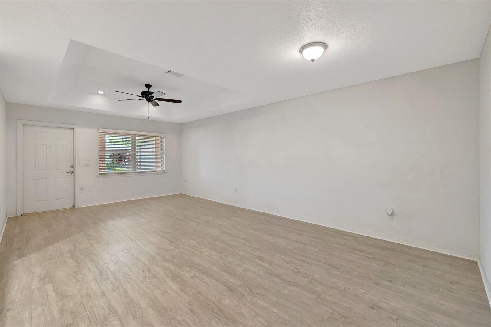 An empty room with light wood-look flooring, white walls, a ceiling fan, and a window — 1804 E Sanderling Lane # B, Fort Pierce FL 34982, FORT PIERCE, FL