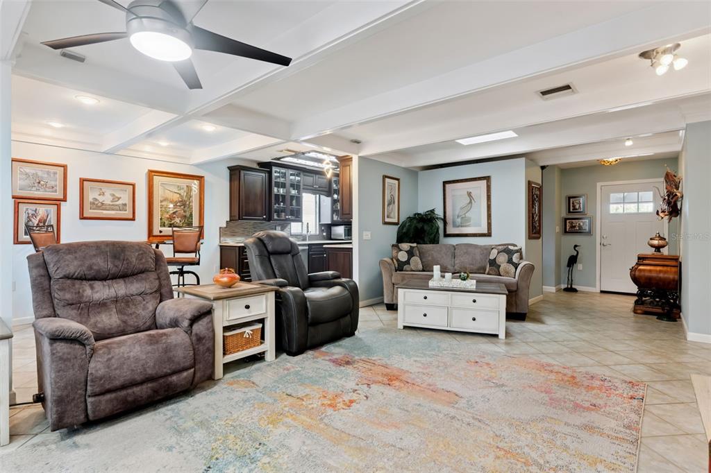 A living room with a ceiling fan, tile floors, and an open kitchen in the background — 13502 COUNTRY CLUB DRIVE, TAVARES, FL