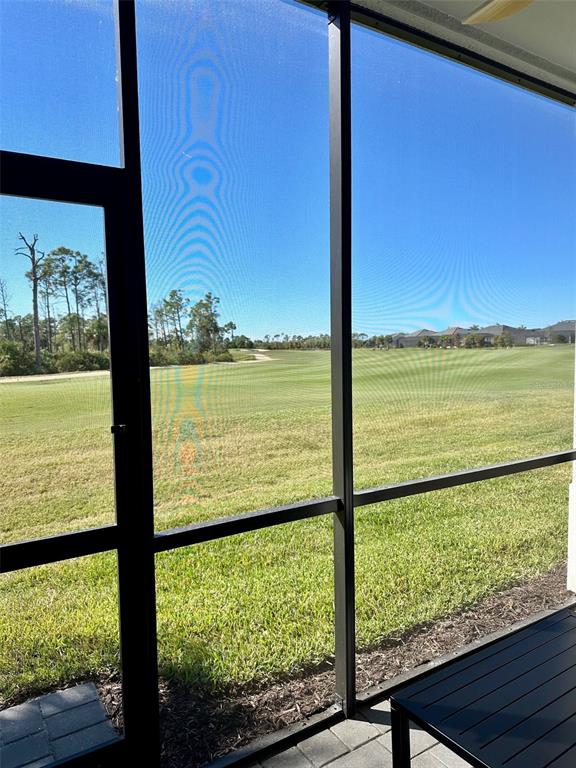 A view of a golf course seen through a screened-in patio enclosure — 17470 OPAL SAND DRIVE UNIT 106, VENICE, FL