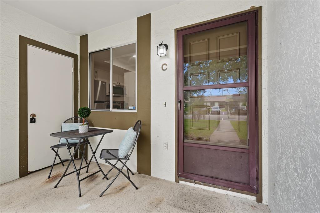 A small patio features a bistro set, a window, and a door with a screen — 2265 BANCROFT CIRCLE S UNIT C, PALM HARBOR, FL