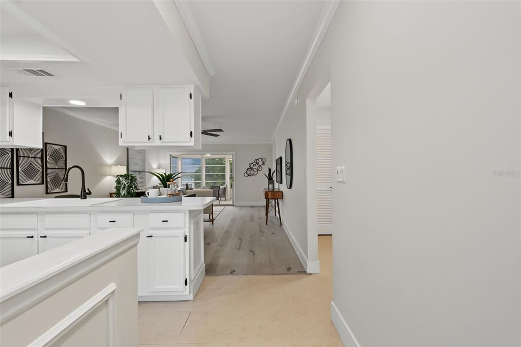 A white kitchen island overlooks a living area with light wood flooring and a patio — 2265 BANCROFT CIRCLE S UNIT C, PALM HARBOR, FL