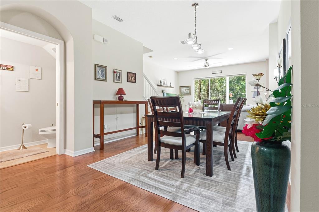 A dining room with a wooden table, chairs, and hardwood floors adjacent to a bathroom — 12658 SILVERDALE STREET, TAMPA, FL