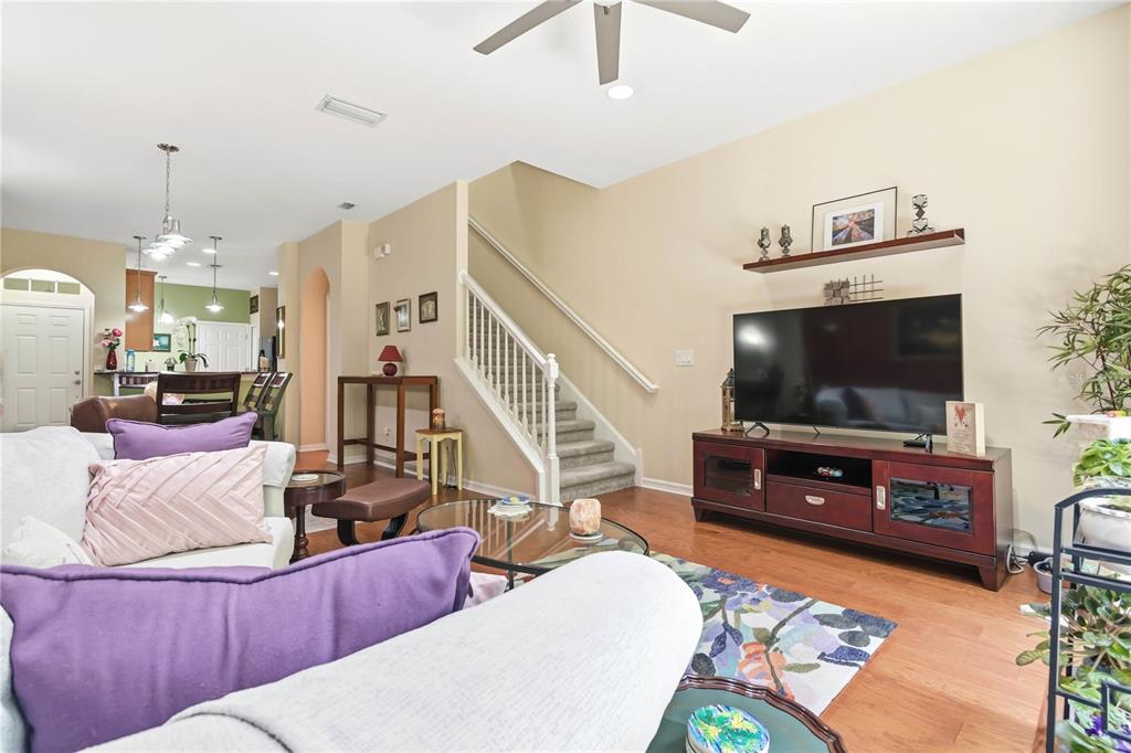 A living room features a television on a wooden stand, a staircase, and hardwood floors — 12658 SILVERDALE STREET, TAMPA, FL