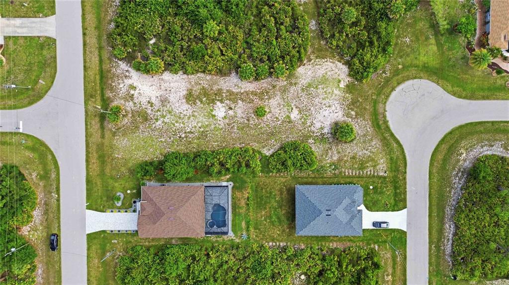 An aerial view shows two houses with driveways situated between two curved residential streets — 116 ANTIS DRIVE, ROTONDA WEST, FL