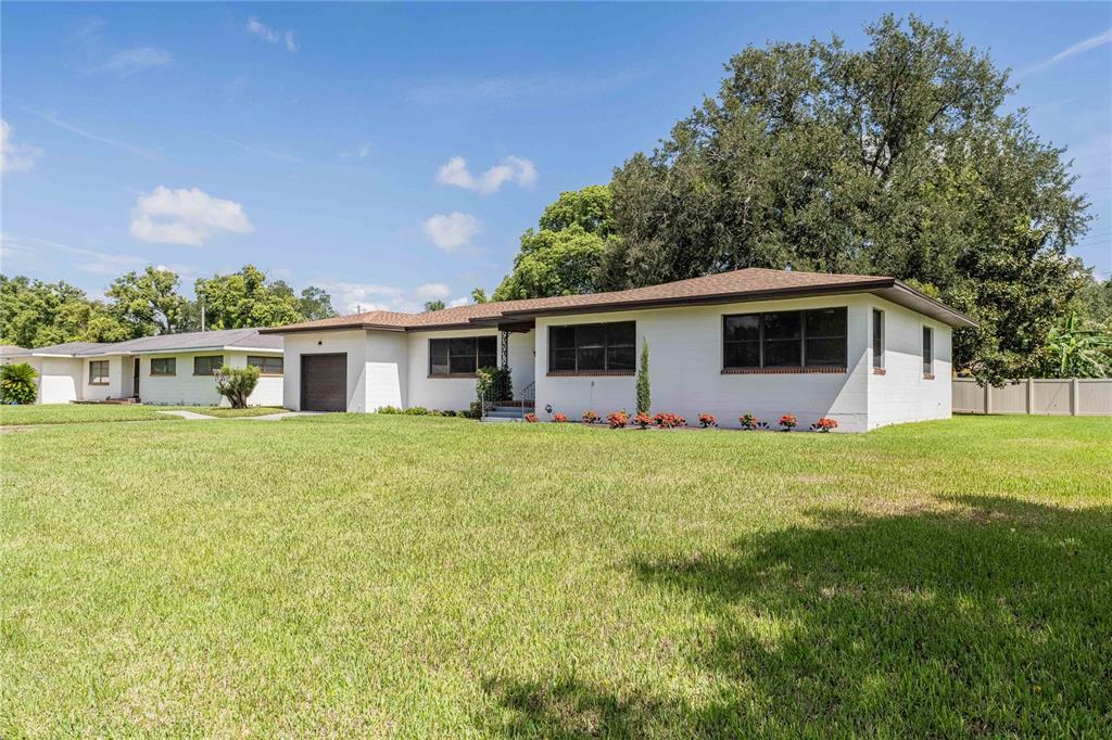A white, single-story ranch-style house with a brown roof sits on a large grassy lawn — 521 BONNIE DRIVE, LAKELAND, FL