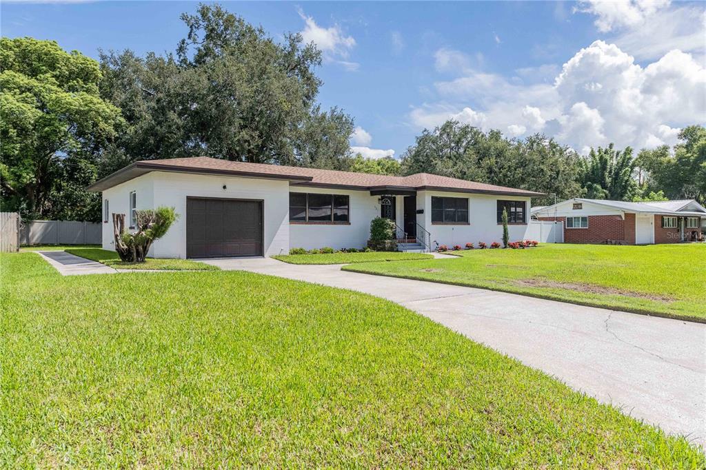 A single-story white house with a brown roof, a one-car garage, and a concrete driveway — 521 BONNIE DRIVE, LAKELAND, FL