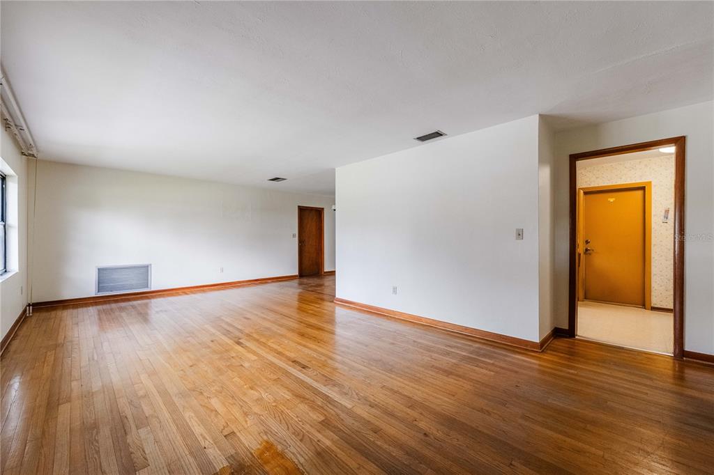 An empty room with hardwood floors, white walls, and two wooden interior doors — 521 BONNIE DRIVE, LAKELAND, FL