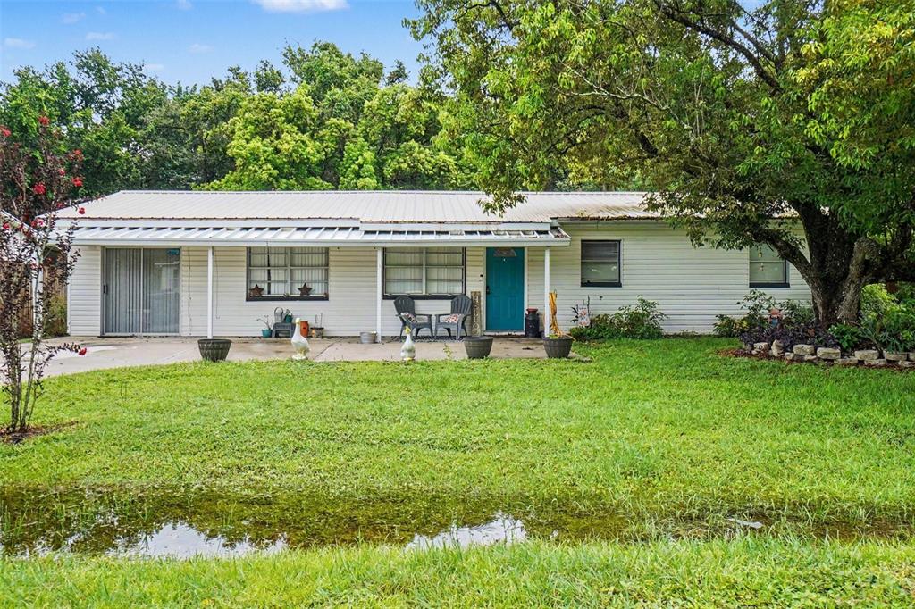 A single-story house with white siding, a metal roof, and a front patio — 3040 STRAWBERRY LANE, LAKELAND, FL