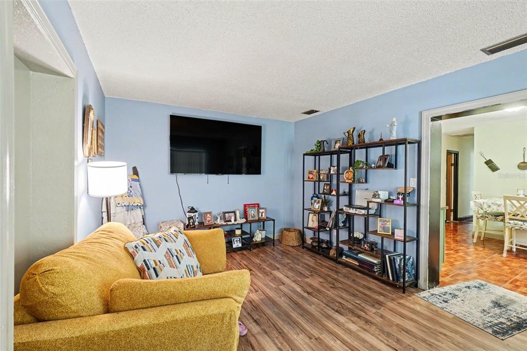 A living room features a yellow sofa, a wall-mounted television, and a tall metal shelving unit — 3040 STRAWBERRY LANE, LAKELAND, FL