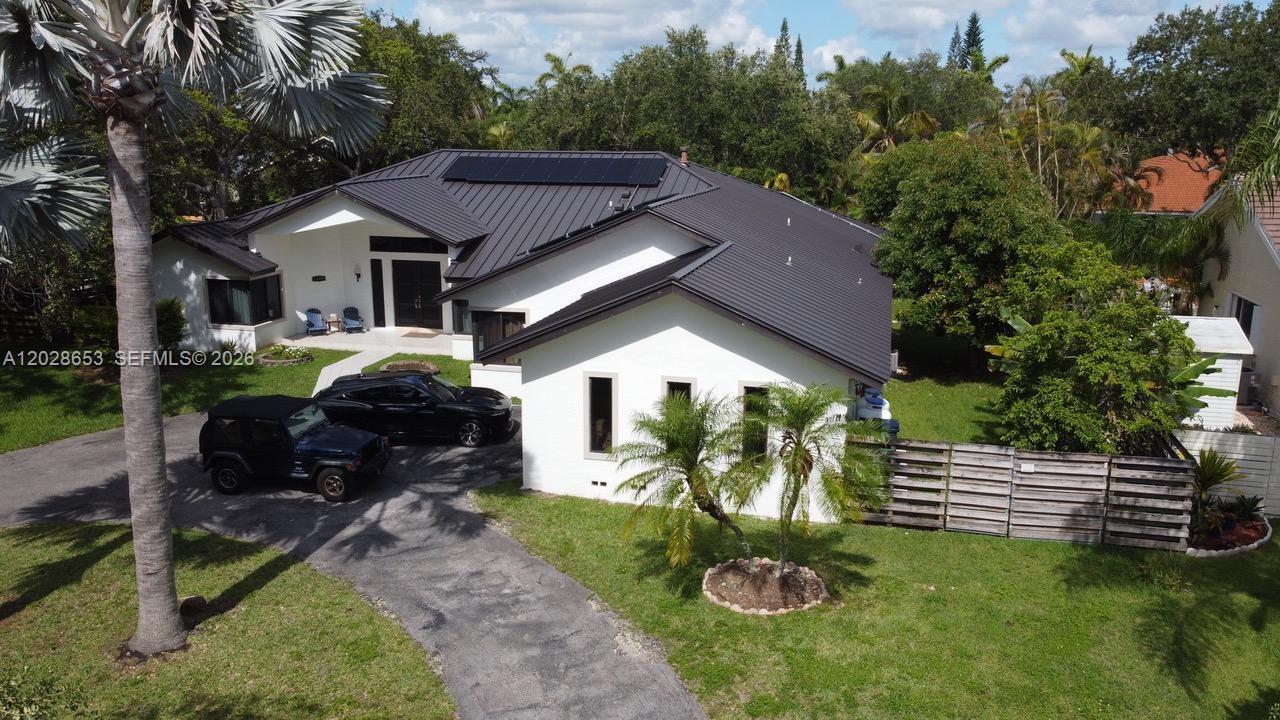 An aerial view shows a white house with a dark metal roof and solar panels — 13324 SW 106th Ave, Miami FL 33176, MIAMI, FL