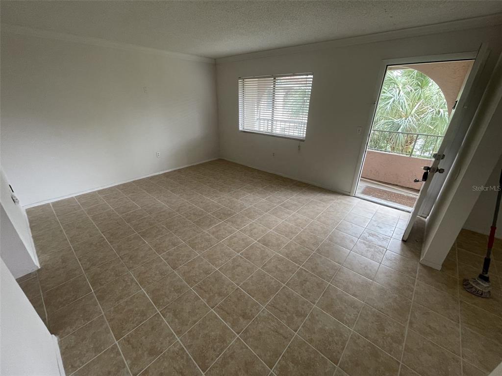 An empty room with beige tile flooring, a window with blinds, and an exterior door — 139 OYSTER BAY CIRCLE UNIT 340, ALTAMONTE SPRINGS, FL