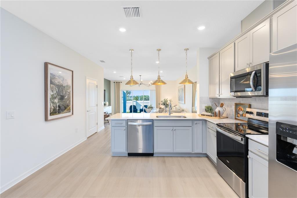 A modern kitchen features light gray cabinets, stainless steel appliances, and a central island — 4348 CHESTER SPRINGS BOULEVARD, DAVENPORT, FL