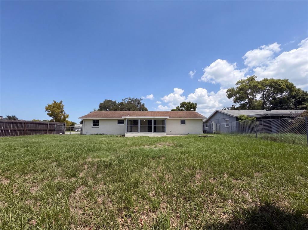 The exterior view shows the back of a single-story house with a screened-in porch — 3518 GORMAN DRIVE, NEW PORT RICHEY, FL