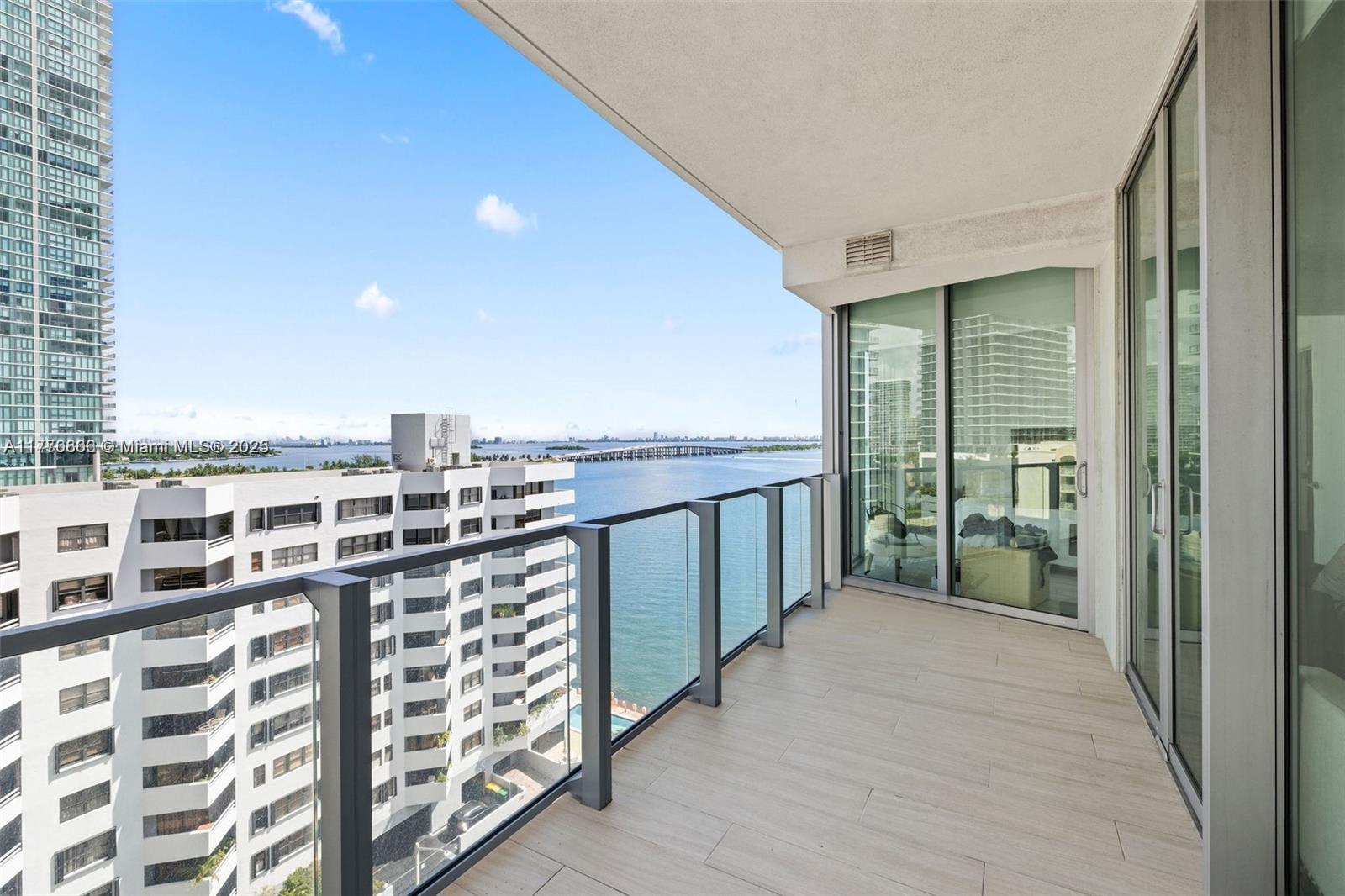 A balcony with glass railings overlooks a bay and city skyline under a blue sky — 2900 NE 7th Ave # 901, Miami FL 33137, MIAMI, FL
