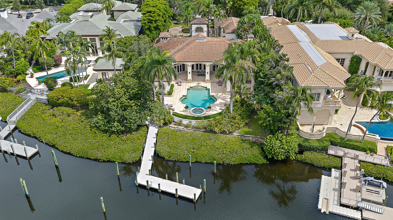 An aerial view shows three waterfront homes with swimming pools, docks, and lush tropical landscaping — 193 Spyglass Court, Jupiter FL 33477, JUPITER, FL