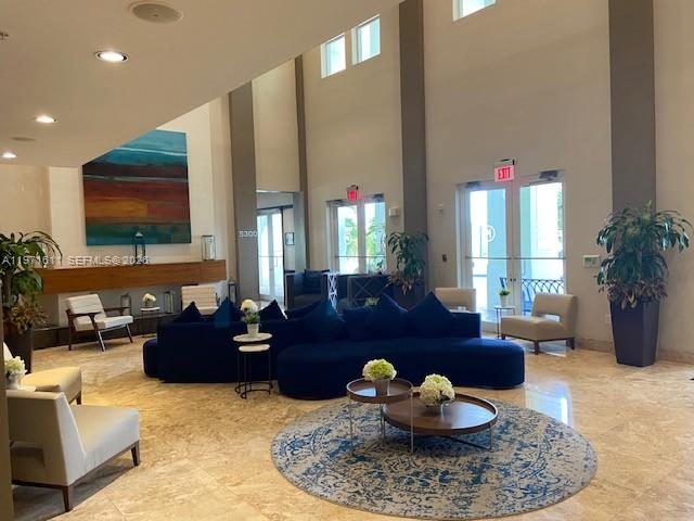 A modern lobby features a large blue sectional sofa, a circular rug, and high ceilings — 5300 NW 87th Ave # 316, Doral FL 33178, DORAL, FL