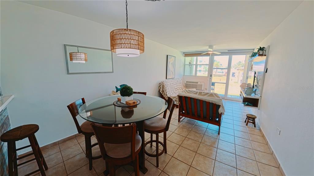 A dining area with a glass table and a living space with tile flooring — 400 COND. HAUDIMAR BEACH APARTMENTS, EDIF. F UNIT F104, ISABELA, PR