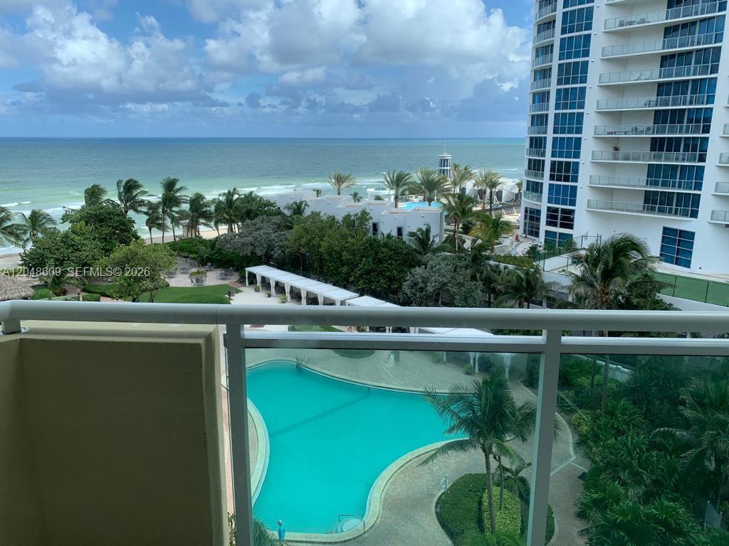 A balcony view overlooks a swimming pool, lush landscaping, and the ocean — 3001 S Ocean Dr # 721, Hollywood FL 33019, HOLLYWOOD, FL
