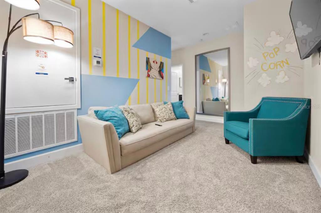 A living room features a beige sofa, a teal armchair, and a popcorn-themed wall mural — 192 VILLA DOMANI CIRCLE, DAVENPORT, FL