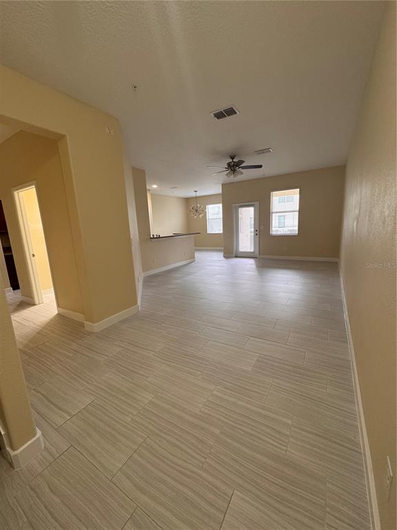 An open-concept living and dining area features light-colored tile flooring and a ceiling fan — 15511 CAMPDEN STREET, WINTER GARDEN, FL