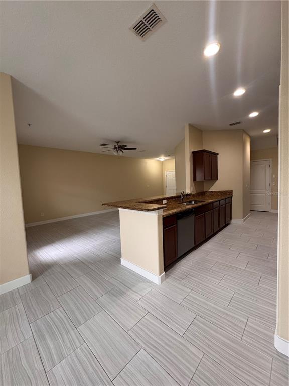 A kitchen with dark cabinets and granite countertops opens into a living area with tile — 15511 CAMPDEN STREET, WINTER GARDEN, FL
