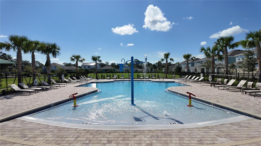 A swimming pool with a central water feature is surrounded by lounge chairs and palm trees — 5844 ALI GRACE WAY, ST CLOUD, FL