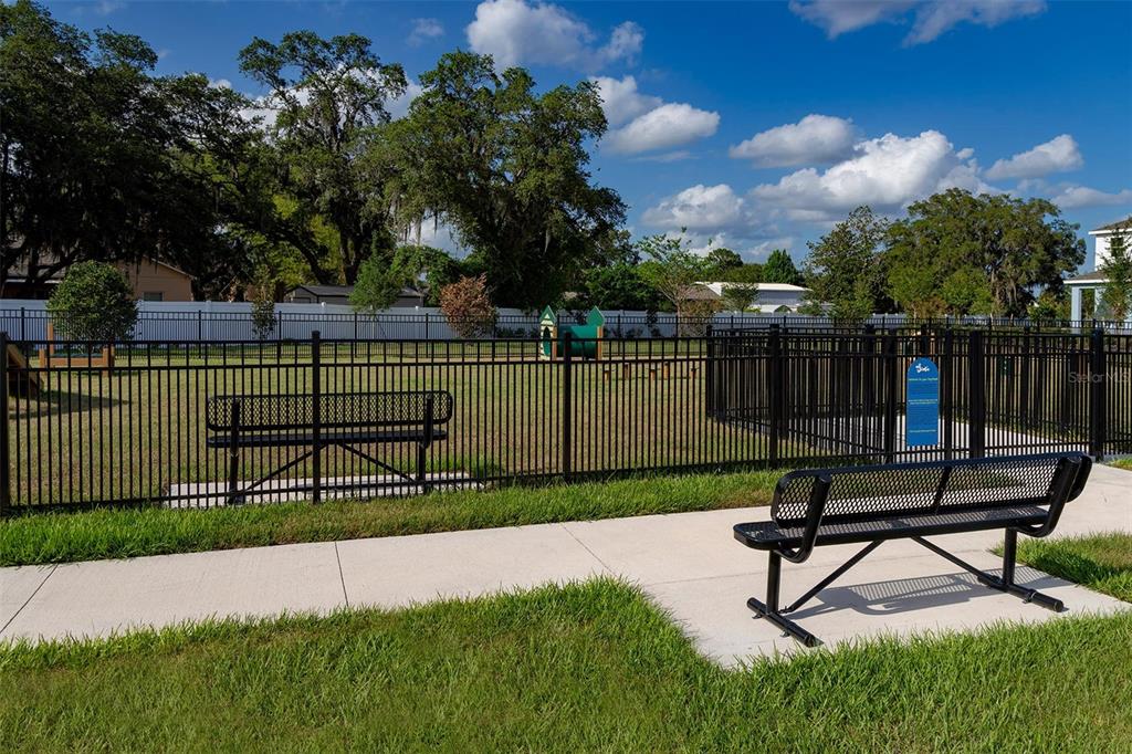 A fenced-in dog park features a concrete walkway, two metal benches, and green grass — 5844 ALI GRACE WAY, ST CLOUD, FL