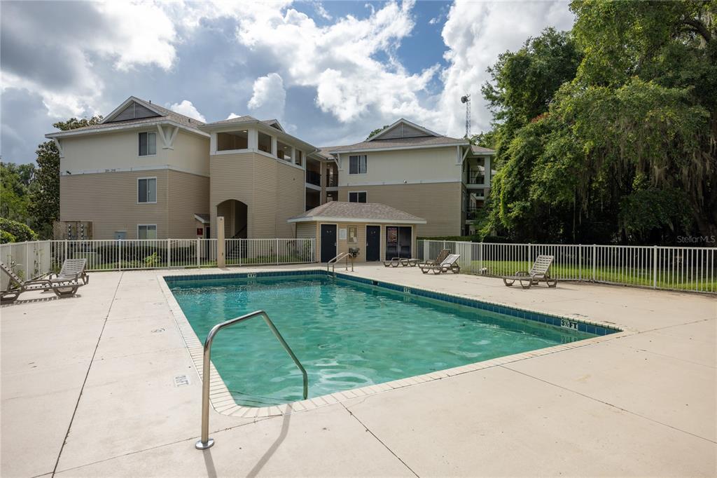 A rectangular swimming pool sits in front of a multi-story apartment building — 3921 SW 34TH STREET UNIT 1C, GAINESVILLE, FL