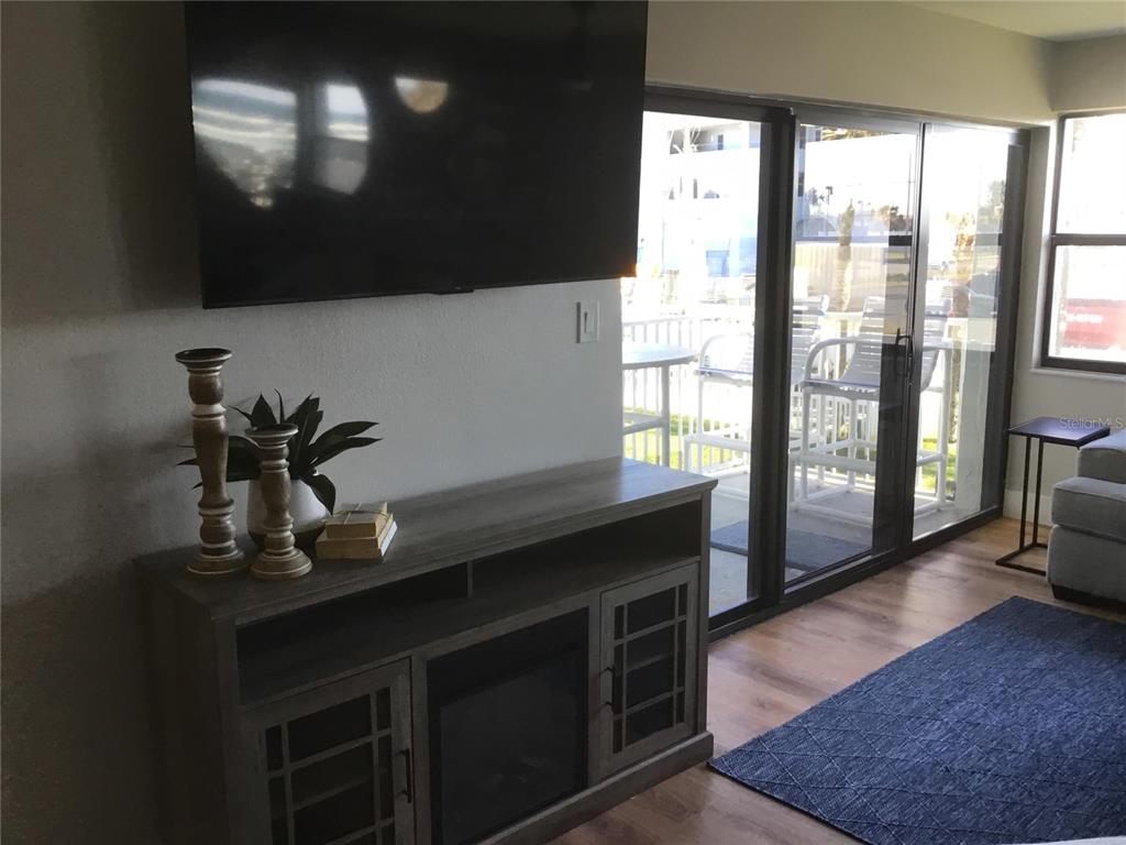A living room features a wall-mounted television above a grey media console with a fireplace — 1571 S ATLANTIC AVENUE UNIT 204, NEW SMYRNA BEACH, FL