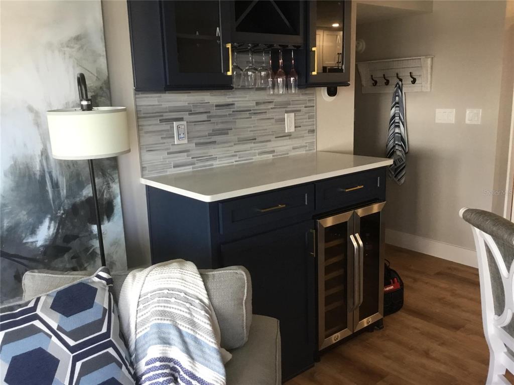 A navy blue wet bar features a white countertop, glass-front cabinets, and a wine cooler — 1571 S ATLANTIC AVENUE UNIT 204, NEW SMYRNA BEACH, FL