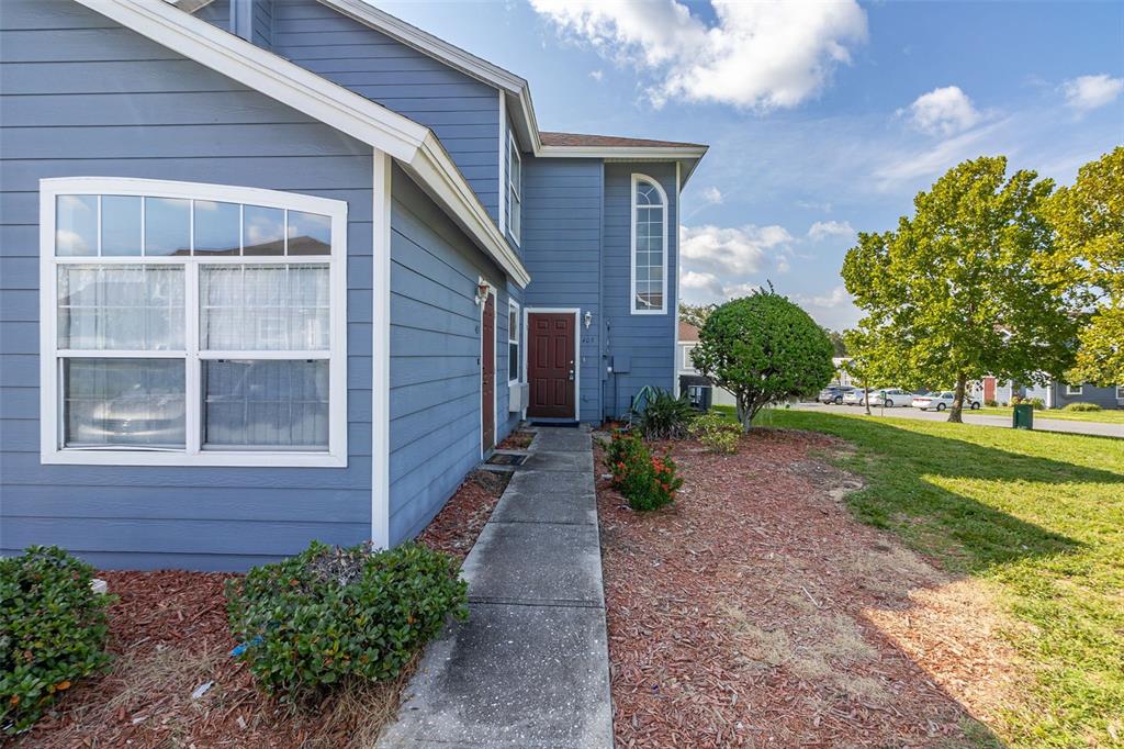 A blue two-story house exterior features a concrete walkway leading to a dark brown door — 403 ORCHID DRIVE, DAVENPORT, FL