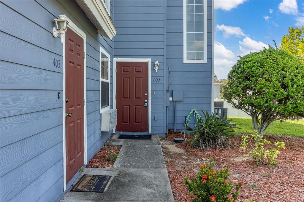 The exterior of a blue-sided building features two red doors labeled 403 — 403 ORCHID DRIVE, DAVENPORT, FL