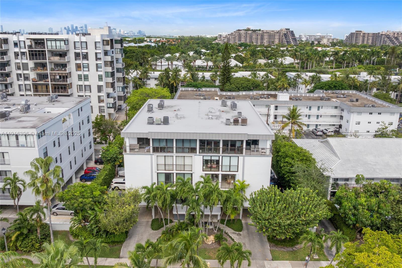 An aerial view shows a white multi-story apartment building surrounded by palm trees and greenery — 155 Sunrise Dr # 4B, Key Biscayne FL 33149, KEY BISCAYNE, FL
