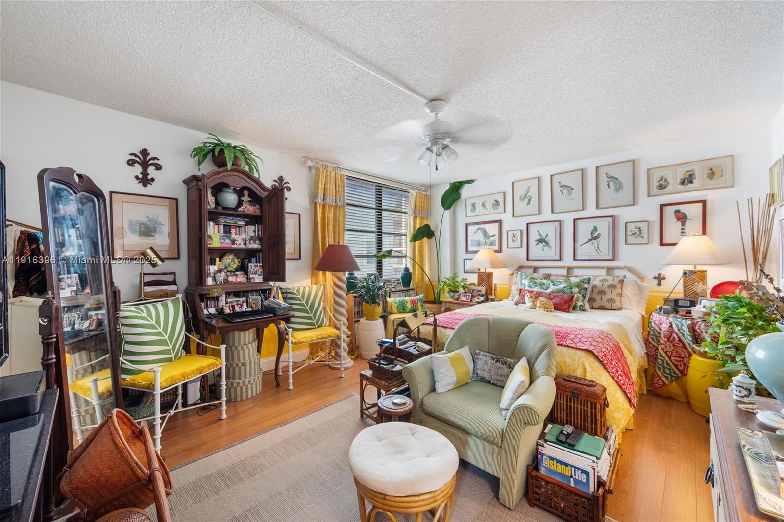 A bedroom features a bed, a green armchair, a wooden hutch, and framed wall art — 155 Sunrise Dr # 4B, Key Biscayne FL 33149, KEY BISCAYNE, FL