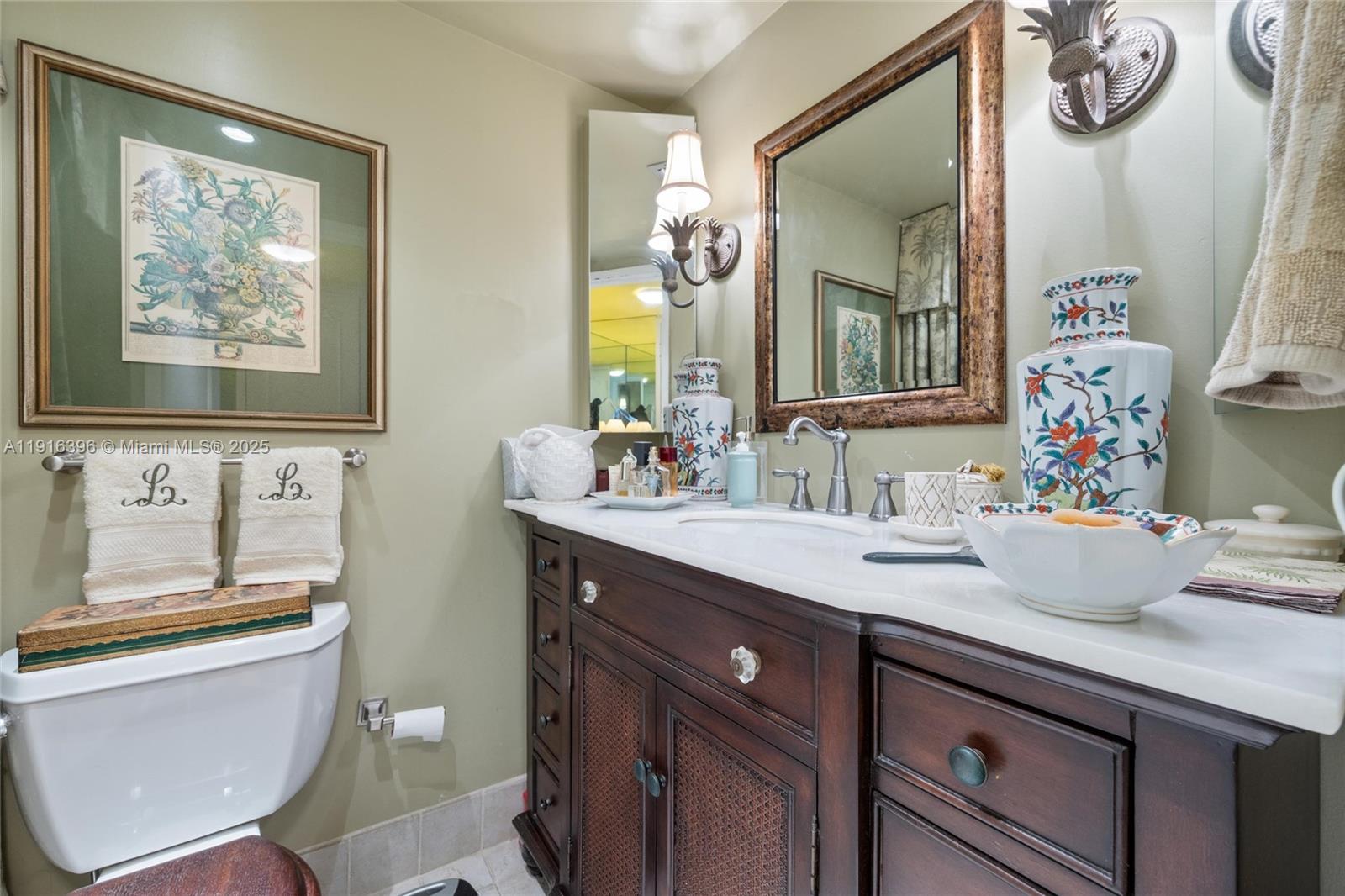 A bathroom features a dark wood vanity with a white countertop and a framed mirror — 155 Sunrise Dr # 4B, Key Biscayne FL 33149, KEY BISCAYNE, FL