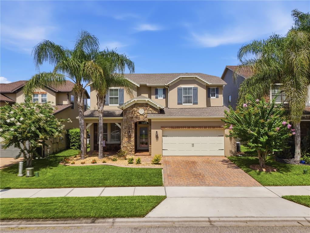 A two-story suburban house with a stone-accented entryway, a two-car garage, and palm trees — 1114 FOUNTAIN COIN LOOP, ORLANDO, FL