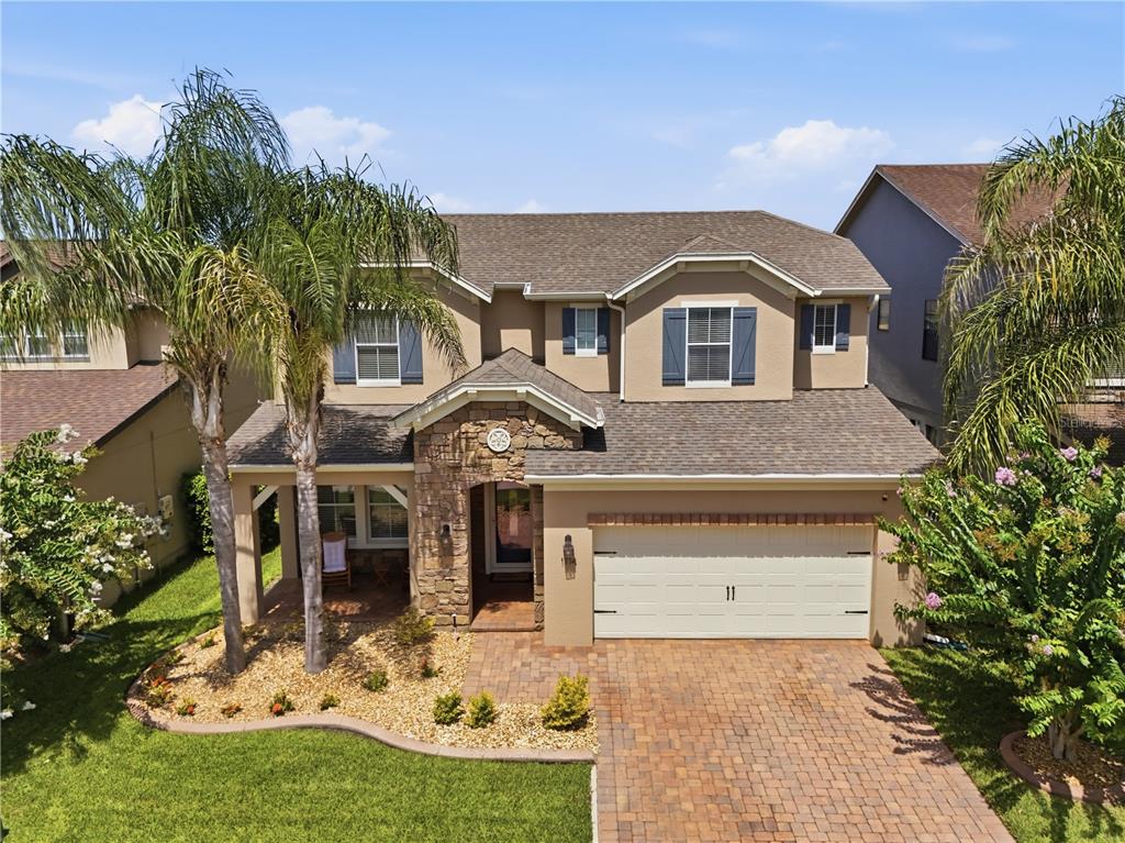 A two-story house with a stone-accented entryway, a two-car garage, and a paver driveway — 1114 FOUNTAIN COIN LOOP, ORLANDO, FL