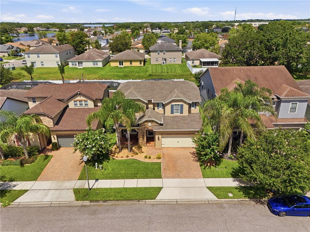 An aerial view shows a suburban street with houses, driveways, and palm trees — 1114 FOUNTAIN COIN LOOP, ORLANDO, FL