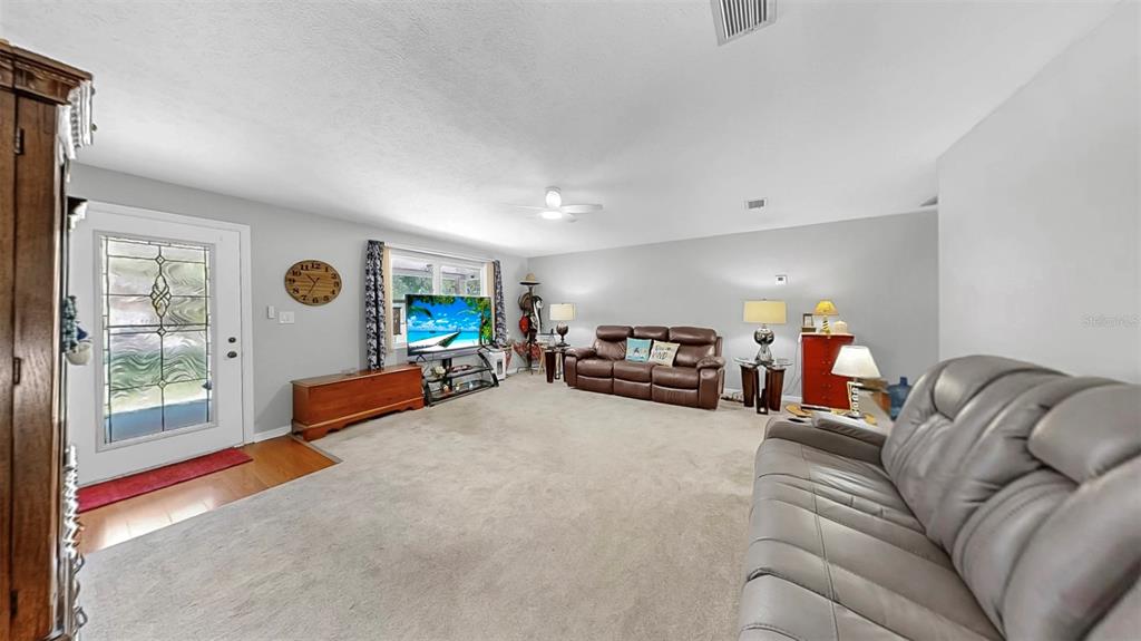 A living room features a brown leather sofa, a grey sofa, and a television — 38919 3RD AVENUE, ZEPHYRHILLS, FL