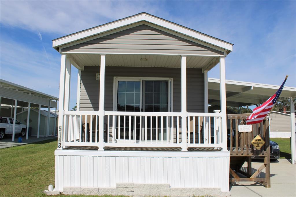 A manufactured home with a front porch, white railings, and a small American flag — 5143 NORTHSHORE DRIVE, POLK CITY, FL