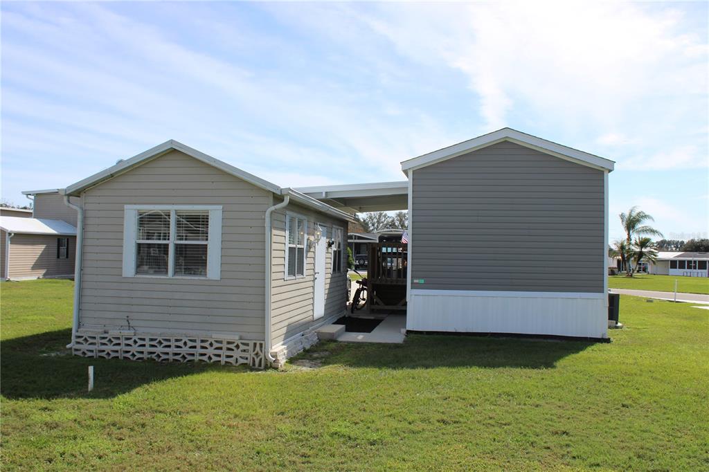 A light-colored manufactured home features a covered carport area between two sections of the structure — 5143 NORTHSHORE DRIVE, POLK CITY, FL