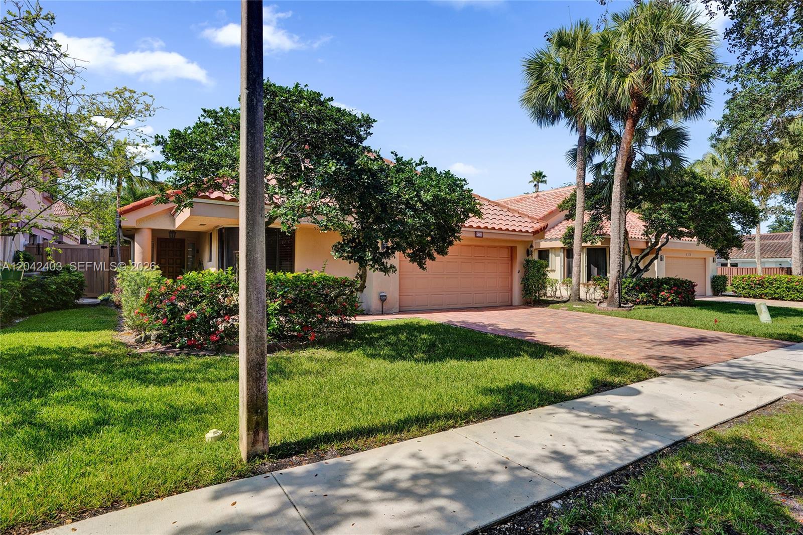 A single-story house with a tile roof, paved driveway, and palm trees in the front yard — 9355 NW 18th Pl, Plantation FL 33322, PLANTATION, FL