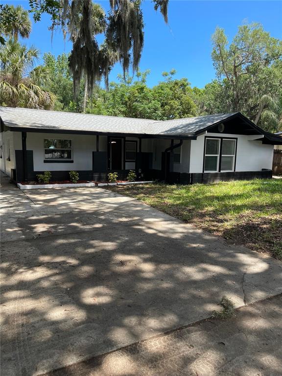A single-story house with a white exterior, black trim, and a concrete driveway — 1139 WOODSIDE DRIVE, DAYTONA BEACH, FL