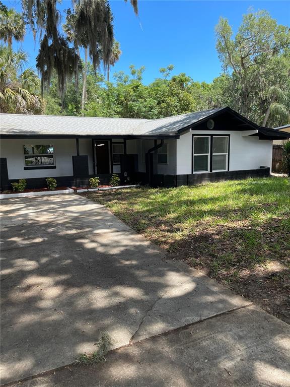 A single-story house with white walls, black trim, and a concrete driveway — 1139 WOODSIDE DRIVE, DAYTONA BEACH, FL