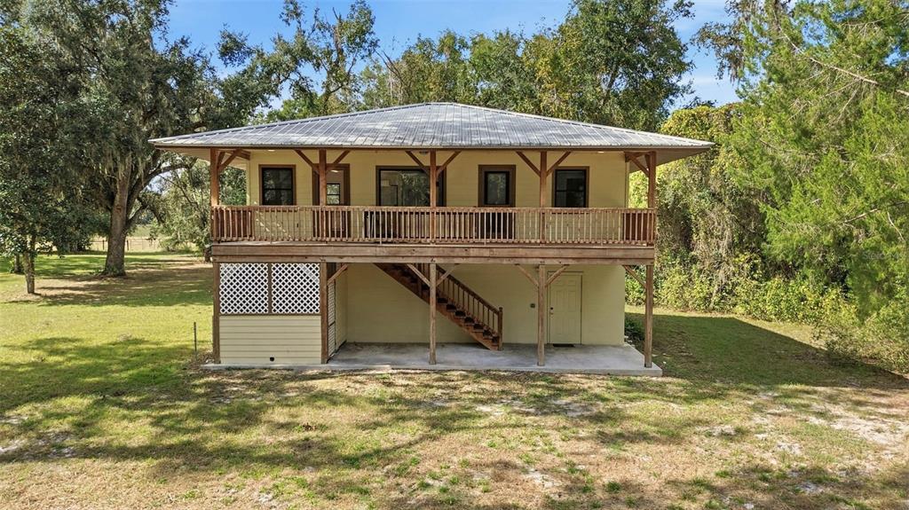 A two-story house with a metal roof, a wooden deck, and an exterior staircase — 5505 CR 634S, BUSHNELL, FL