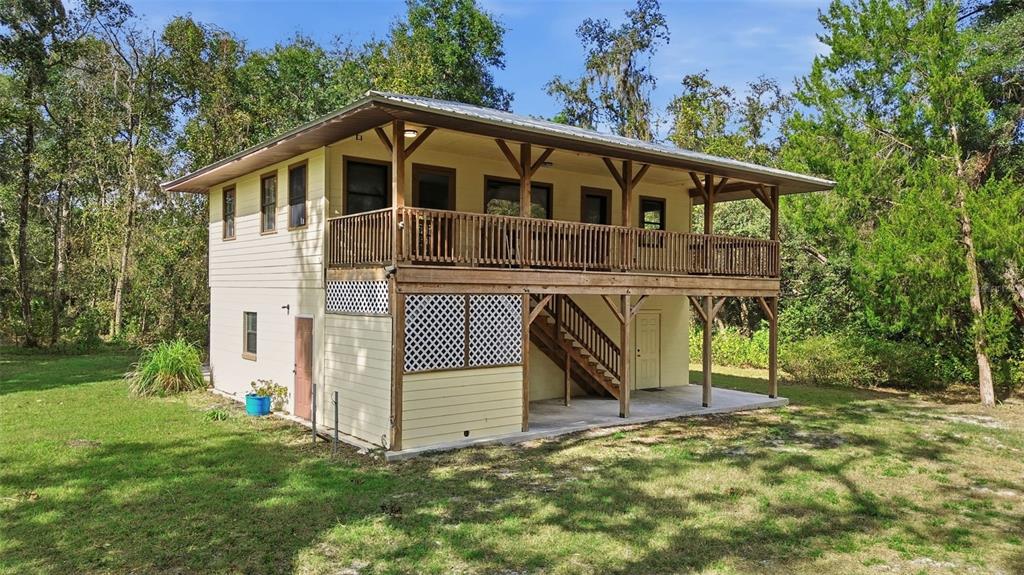A two-story house with a wrap-around wooden deck and lattice skirting sits in a yard — 5505 CR 634S, BUSHNELL, FL