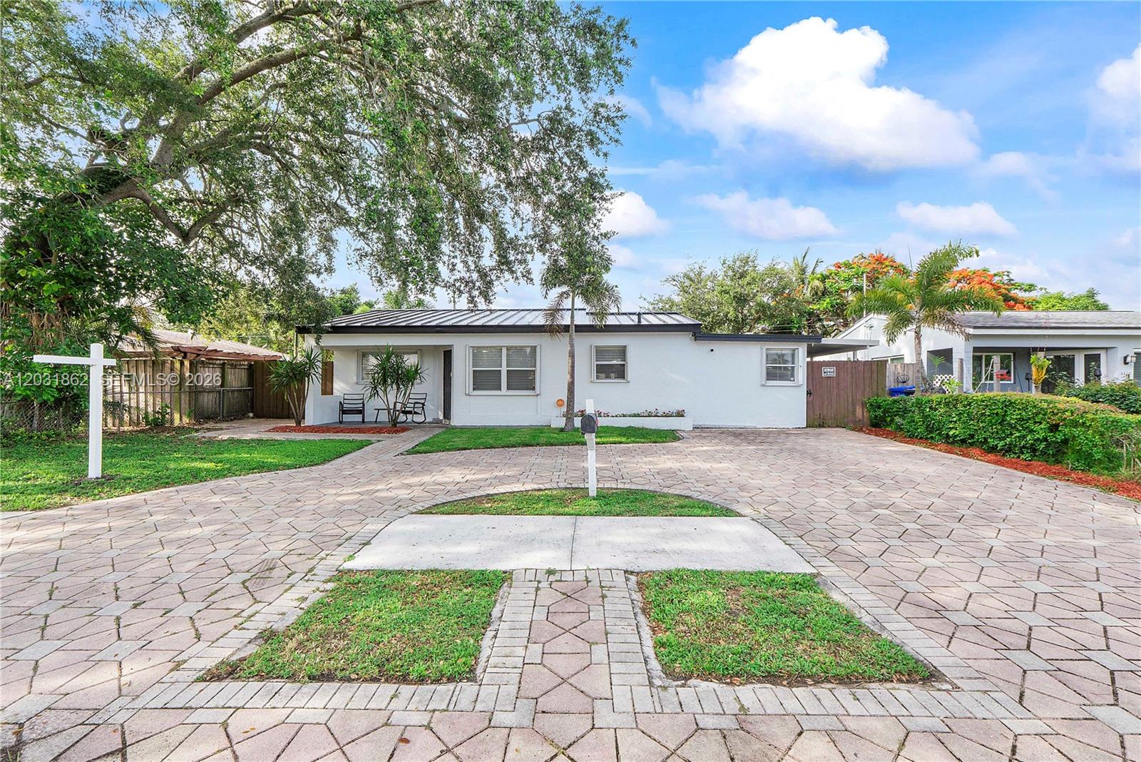 A white single-story house features a large paved driveway with integrated grass patches — 6810 Douglas St, Hollywood FL 33024, HOLLYWOOD, FL